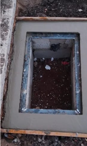 Weathered rectangular window with blue frame set in deteriorating concrete wall, showing dark interior space